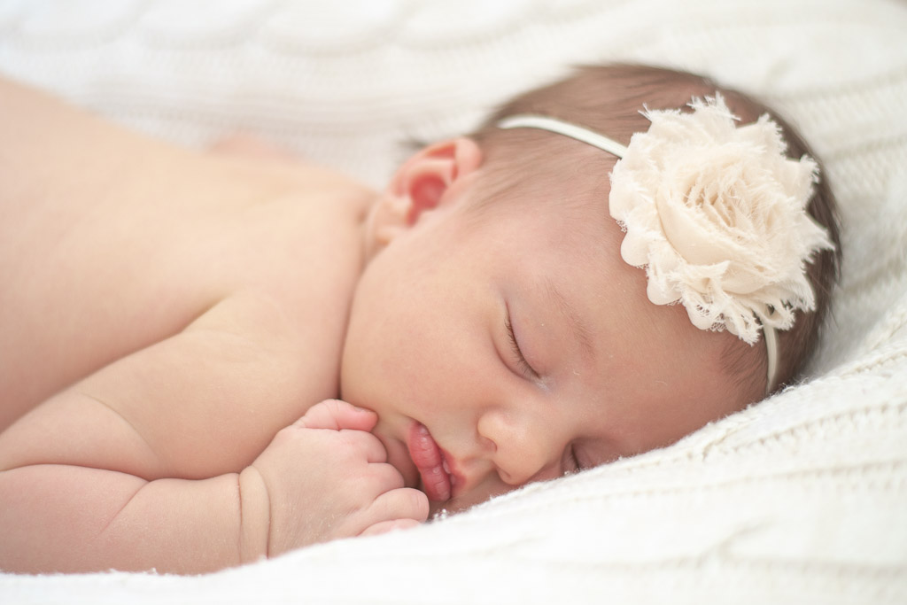 Baby girl with white headband and white blanket