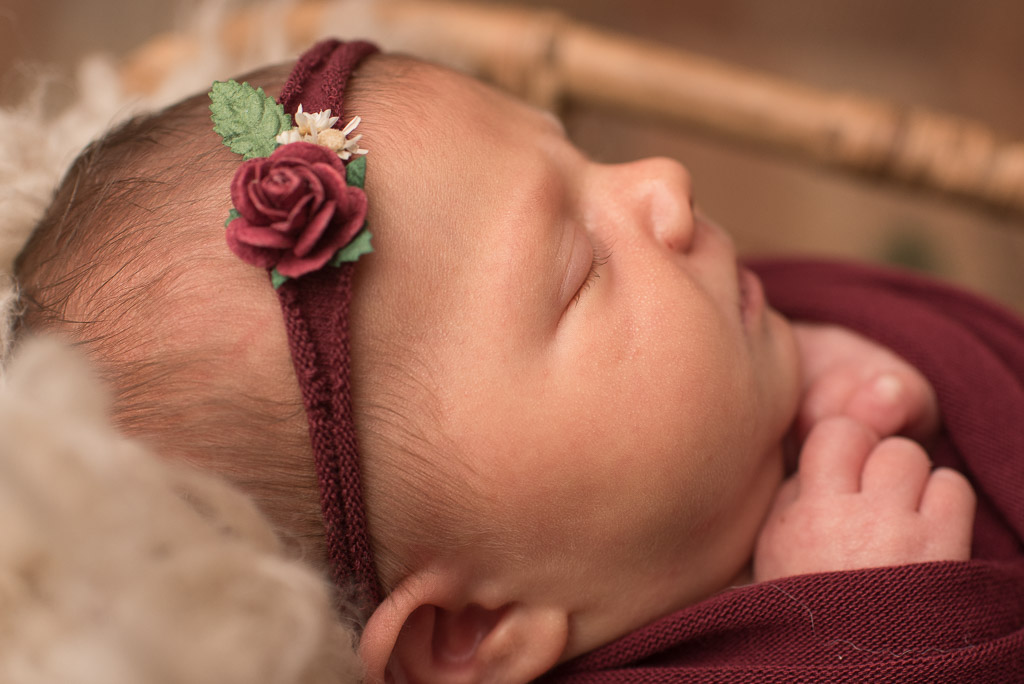 Close up image of newborn girl wrapped in red wrap with red headband | CT studio newborn session