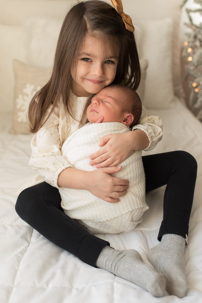 Sister holding newborn brother at newborn session