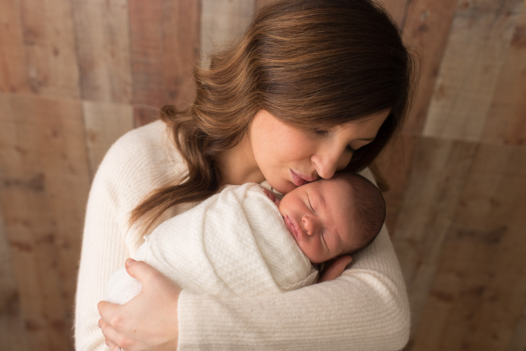 Newborn boy wrapped in white at newborn session with mom