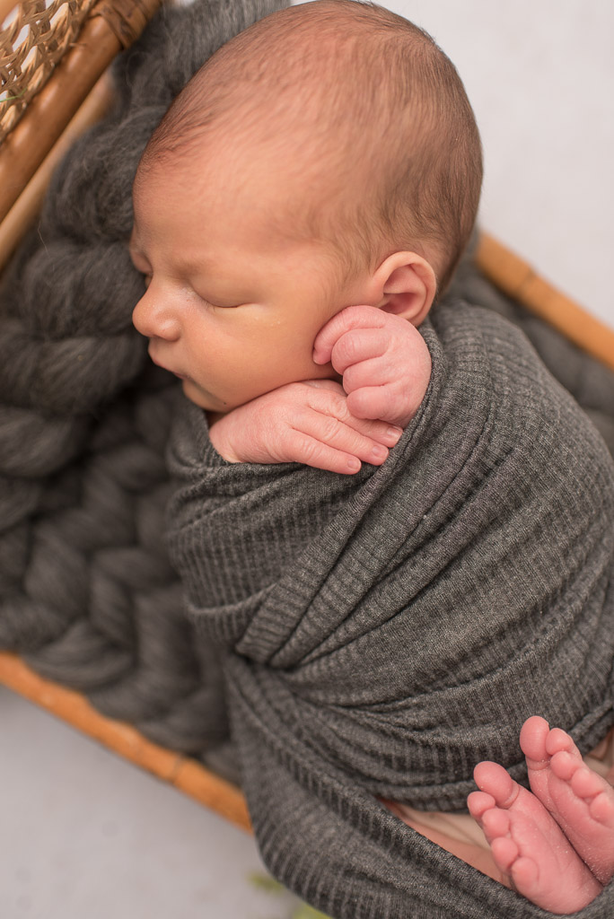 Newborn boy wrapped in gray at newborn session