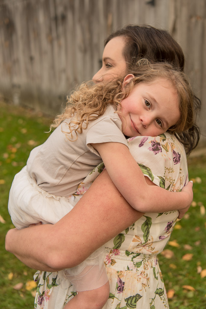 Mom in floral dress hugging girl in white dress | Sharon Leger Photography