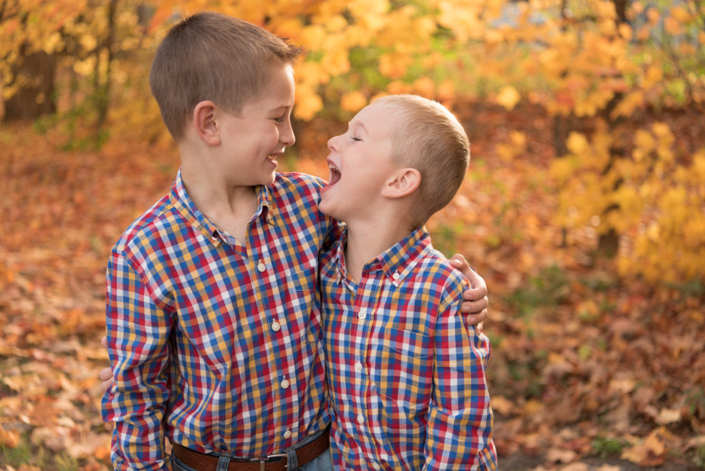 Two brothers laughing at each other in fall