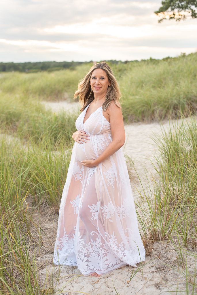 Pregnant mother standing in dune grass at the beach
