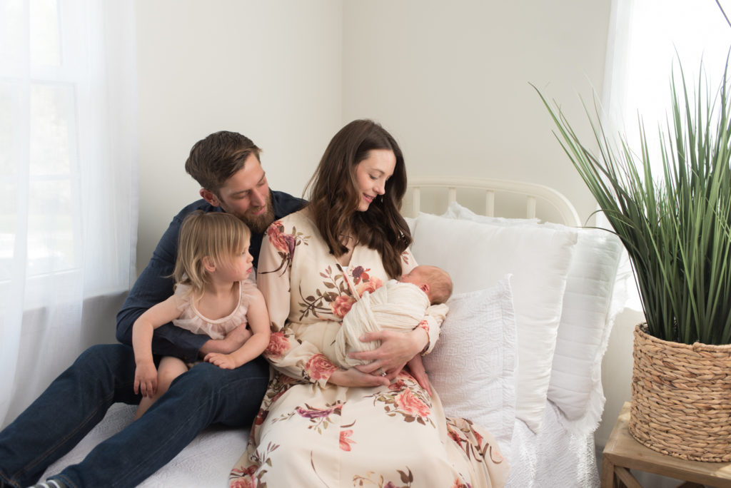 Family looking at new baby in white studio