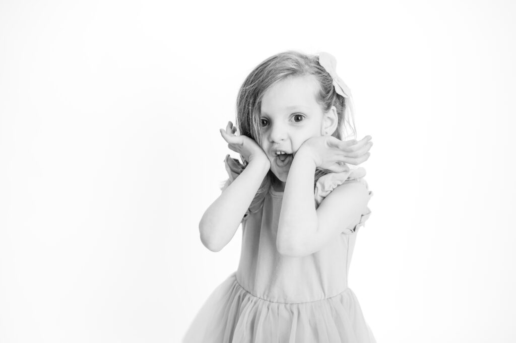 A three-year old girl making a funny face at the camera in black and white
